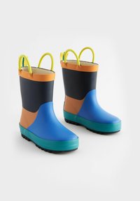 Bottes en caoutchouc imperméables colorées en bleu, orange, noir et vert. Présentent une semelle texturée et des poignées doubles pour un enfilage facile.