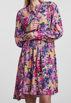 Robe fleurie avec imprimé multicolore comprenant des teintes de rose, violet, jaune et vert. Manches longues, devant boutonné, et taille froncée.
