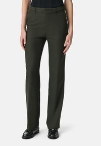 Pantaloni su misura verde scuro con design a gamba dritta, texture liscia e piega frontale sottile; abbinati a calzature nere.