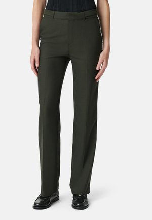 Pantaloni su misura verde scuro con design a gamba dritta, texture liscia e piega frontale sottile; abbinati a calzature nere.