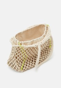 Sac en crochet beige avec une doublure intérieure douce, doté d'une fermeture par cordon de serrage et d'accents vert néon ; forme ronde avec deux anses.