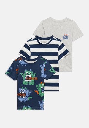 Τρία παιδικά κοντομάνικα μπλουζάκια: ανοιχτό γκρι με μικρό τέρας, ναυτικό μπλε με λευκές ρίγες και ναυτικό μπλε με πολύχρωμα παιχνιδιάρικα σχέδια τεράτων και το κείμενο "GRAAAH!".