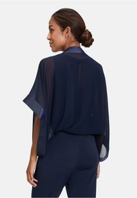 Navy sheer kimono with wide sleeves and satin trim, featuring a subtle back opening. Lightweight, flowing fabric enhances movement.