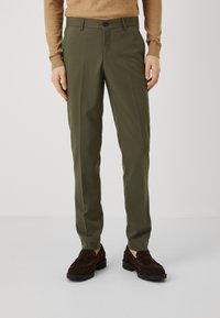 Olive green trousers with a tailored fit, featuring a front zipper, button closure, and side pockets. Worn with brown suede loafers.