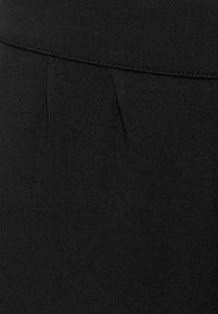 Svart tyg med en slät yta har en veckdetalj och ett brett midjeband, vilket betonar en ren och minimalistisk design.