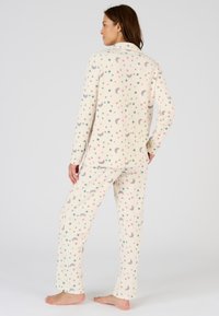 Fleece pyjama's met een crèmekleurige achtergrond en kleurrijke sterren- en maanpatronen. De set omvat een lange mouw top en bijpassende broek.