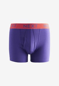 Lila pamut boxer alsónadrág, elülső nyitással, piros derékrésszel, amelyen kék betűkkel a "NEXT" felirat található. Simogató tapintású és testhezálló kialakítású.