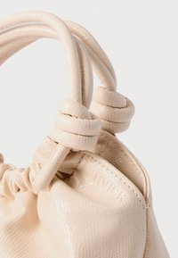 Beige leren handtas met een gestructureerd oppervlak, knoopgrepen en een geplooide bovenkant. Voorzien van een geperst logo en een gladde binnenvoering.