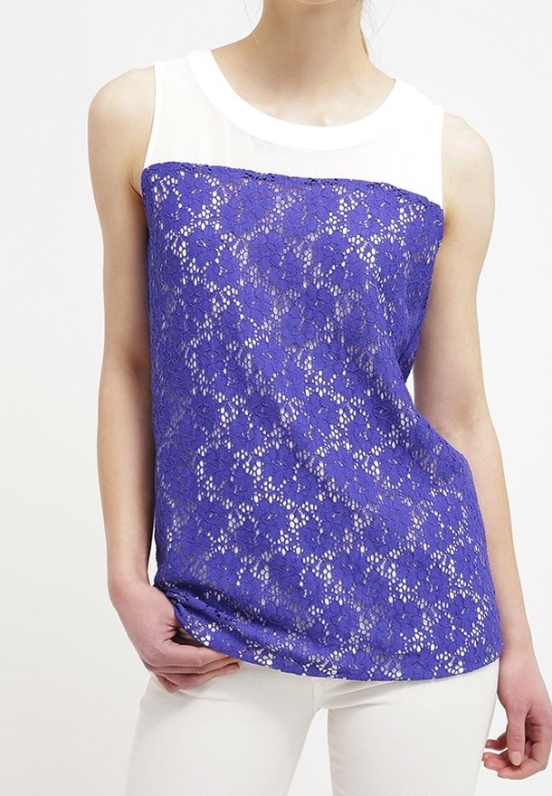 Top di pizzo viola con una pannello bianco sulle spalle. Motiviflorali con sezioni trasparenti. Texture liscia e vestibilità casual, adatto per un abbigliamento informale.