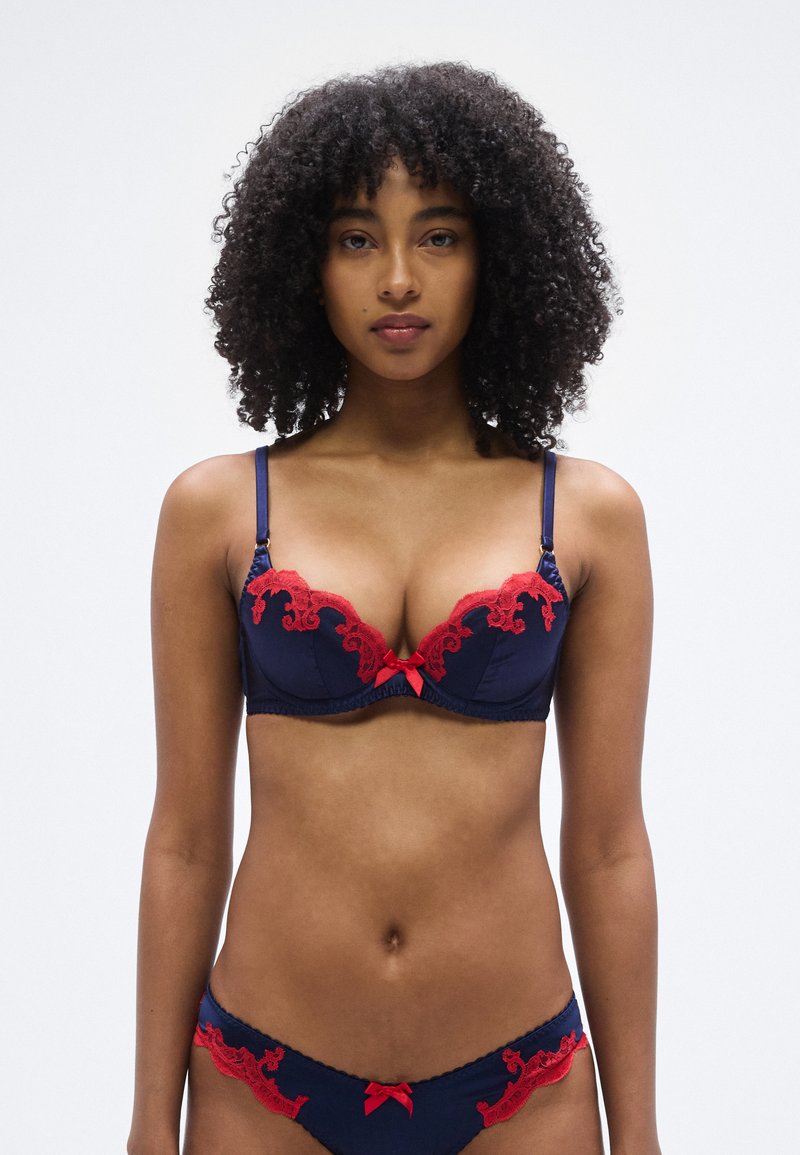 Granatowy koronkowy biustonosz z czerwonymi kwiatowymi akcentami, z fiszbinami, regulowanymi ramiączkami i małą kokardką na środku. Dopasowane bikini.
