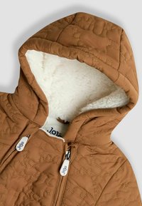 Hnedá prešívaná bunda s kapucňou a mäkkou bielou fleecovou podšívkou. Obsahuje predný zips a akcentové švy v vlnkovanom vzore.