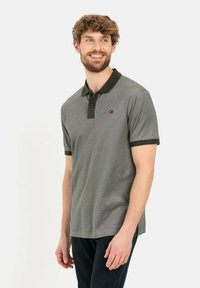 Graues Poloshirt mit einem dunkelgrünen Kragen, kurzen Ärmeln und einem kleinen gestickten Logo auf der Brust. Hergestellt aus weichem, glattem Stoff.