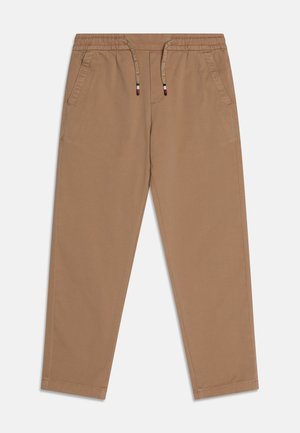 Jasnobrązowe zwężane spodnie z elastycznym pasem, przednimi kieszeniami i sznurkami z białym napisem oraz czerwonymi, białymi i czarnymi końcówkami.