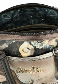 Handtasche mit mehreren Fächern und einem gemusterten, lackierten Außendesign. Verfügt über ein dunkles Innenfutter mit Text und einem metallischen Markenakzent.