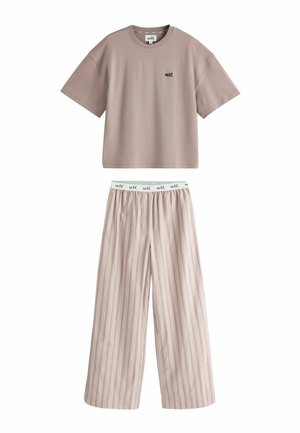 Person wearing a loose brown t-shirt with "self." printed and a striped skirt, hand tucked into the skirt pocket.