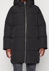 Black puffer coat with a hood, featuring a quilted design, front zipper, and side pockets. Made of smooth, lightweight material.