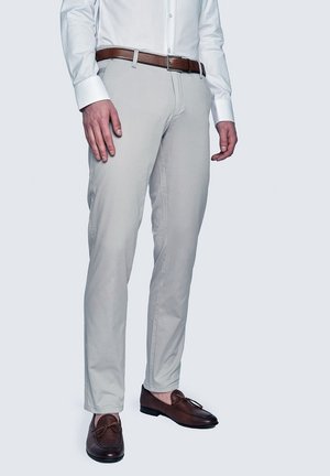 Jasnoszare chinos wykonane z bawełny, w slim fit, z kieszeniami z przodu i brązowym skórzanym paskiem, w zestawie z brązowymi mokasynami.