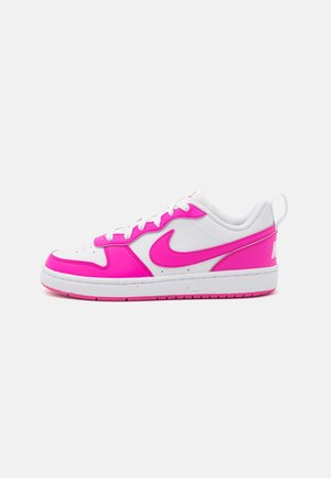 Λευκά και φωτεινά ροζ αθλητικά παπούτσια Nike με λείο δερμάτινο φινίρισμα, τρυπητή μύτη, λευκές κορδόνες και ροζ σόλα με λογότυπο στη φτέρνα.