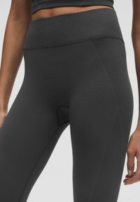 Hooggewaardeerde zwarte leggings met een geribde tailleband en een gladde textuur, voorzien van platte naden en een aansluitende snit.