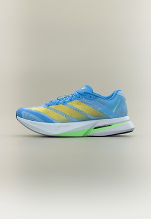 Modrá a žltá ľahká bežecká obuv s vrchnou časťou z mriežky, bielou a zelenou tlmenou podrážkou a šnúrkami na svetlosivom pozadí.