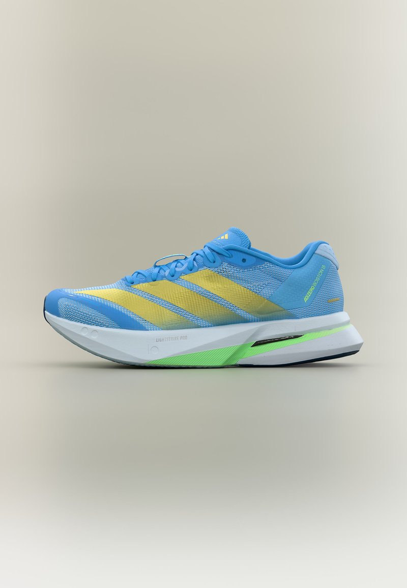 Chaussure de course légère bleue et jaune avec dessus en maille, semelle coussinée blanche et verte, et lacets sur fond gris clair.