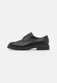 Scarpa da uomo in pelle nera con texture liscia, punta tonda, tacco basso e design semplice con lacci. Presenta dettagli di cucitura discreti.
