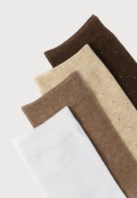 Fire par sokker vist. Farverne inkluderer hvid, beige, lysebrun og mørkebrun. Varierede teksturer med striber og et prikket mønster.