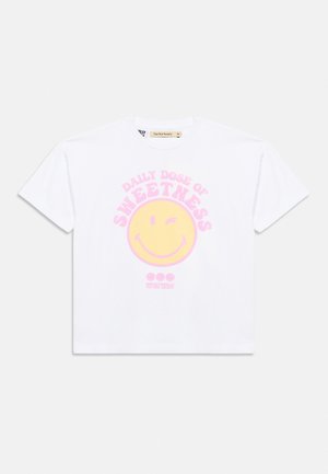 Hvid T-shirt med korte ærmer med et gult blinkende smiley-ansigt og pink tekst med teksten "Daily dose of sweetness" på forsiden.