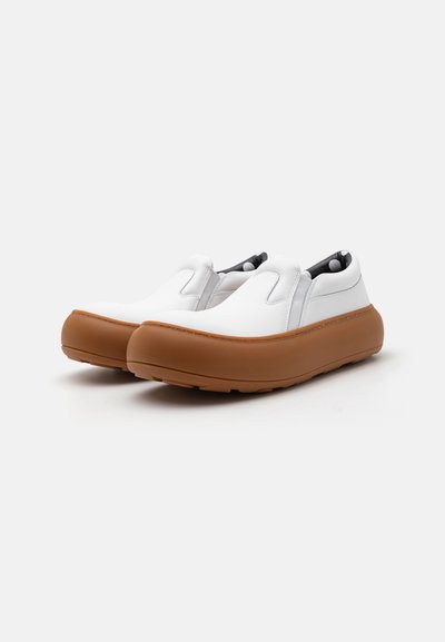 White slip-on shoes with a smooth leather upper and rubber sole in tan. Features elastic side panels for easy wear and a rounded toe design.