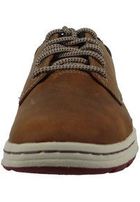 Scarpa in pelle marrone con lacci, cuciture beige a contrasto, punta rotonda e suola bianca. Presenta lacci con motivo e una superficie liscia.