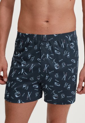 Shorts en modal bleu marine ornés d'un motif d'icônes liées au ski et de noms suisses, fabriqués à partir d'un matériau doux et respirant avec une taille élastique.