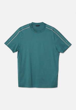 Teal t-shirt med rund hals lavet af bomuld med korte ærmer. Har hvid "Emporio Armani" branding langs skuldrene. Glat tekstur.