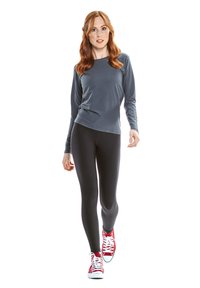 Long-sleeve gray top made of soft fabric, paired with form-fitting black leggings and red sneakers with white laces.