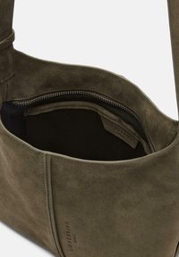 Zielona oliwkowa torba z zamszu z zamknięciem na zamek błyskawiczny oraz wewnętrzną kieszonką. Charakteryzuje się gładką, matową teksturą i akcentami ściegów.