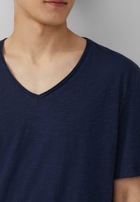 Granatowa koszulka typu v-neck, krótki rękaw, miękka tekstura, lekki materiał, subtelny połysk, o czystym i prostym wzorze.