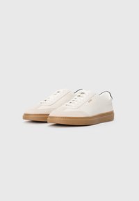 Hvide sneakers med en kombination af glatte og strukturerede materialer, udstyret med en gummisål, rund tå og diskret branding i orange.