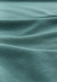 Țesătură din bumbac în nuanțe de teal estompat, prezentând o textură moale cu drapaje delicate și un model de țesătură fină. Suprafață netedă, fără embellishments vizibile.