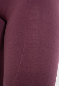 Burgundy urheiluleggingsit, jotka on valmistettu venyvästä kankaasta, ja joissa on upea kankaanpintarakenne sekä hienovaraisia sävyjä sivuilla.