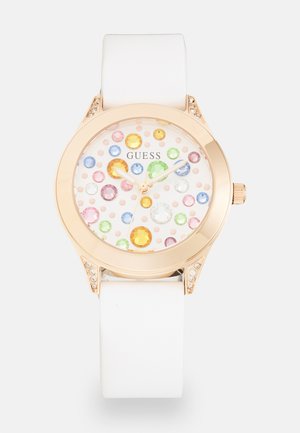 Orologio Guess con cinturino in silicone bianco, cassa in oro rosa e quadrante a pois decorato con gemme colorate e un accento in cristallo.