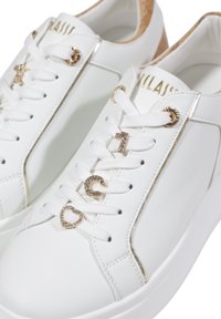 Sneaker in pelle bianca con accenti dorati, clips decorative per i lacci (1, C, cuore) e una suola testurizzata per una migliore aderenza.