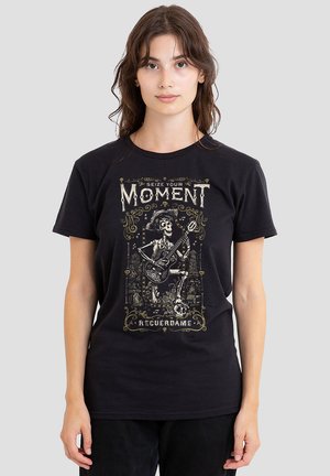 Schwarzes T-Shirt mit einem Grafikdesign im Vintage-Stil, das eine Skelettfigur zeigt, die Gitarre spielt, mit kunstvollem Text und dekorativen Elementen.