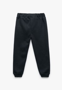Pantalones deportivos negros con una textura de punto suave, cinturilla elástica y diseño con puños en los tobillos. Sin patrones ni adornos visibles.