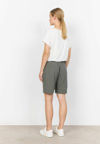Shorts gris avec une taille élastique, associés à un t-shirt blanc ample. Design simple et décontracté avec une texture douce. Baskets blanches.
