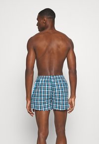 Herrenbadehosen mit einem blau-schwarz-weißen Karomuster, elastischem Bund und einem leichten, schnell trocknenden Stoff.
