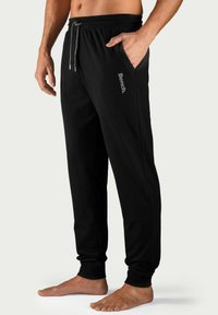 Zwarte joggingsbroek van zacht materiaal met een elastische tailleband, koorddetail, zijzakken en de "Bench." logo-prints op het been.