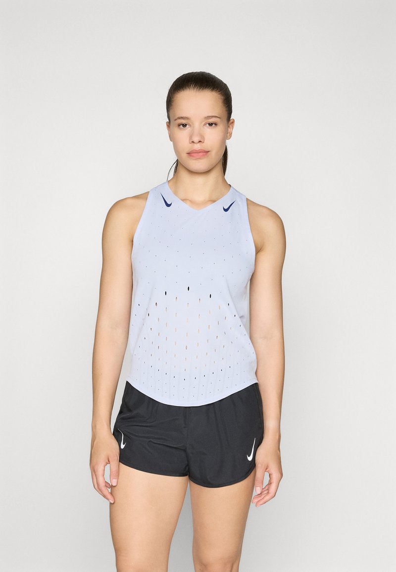 Lichtblauw mouwloos sporttanktop met perforaties, uitgerust met een ronde hals en donkerblauwe logo-accenten. Gekleed met zwarte shorts.
