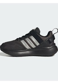 Chaussure de sport noire avec une tige en maille, trois rayures argentées, un col rembourré et une épaisse semelle noire. Présente une languette à l'arrière.