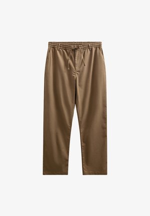 Brune afslappede bukser med elastisk talje og snøre, lige ben og sidelommer, vist fladt på en hvid baggrund.