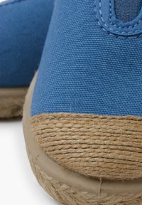 Scarpe slip-on blu in canvas con punta arrotondata, dettagli in juta sul davanti e upper testurizzato. La suola ha una finitura liscia.