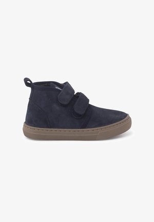 Stivaletti alla caviglia in suede blu navy con due cinturini in Velcro, punta tonda e suola in gomma marrone chiaro. Presentano un collo imbottito per il comfort.